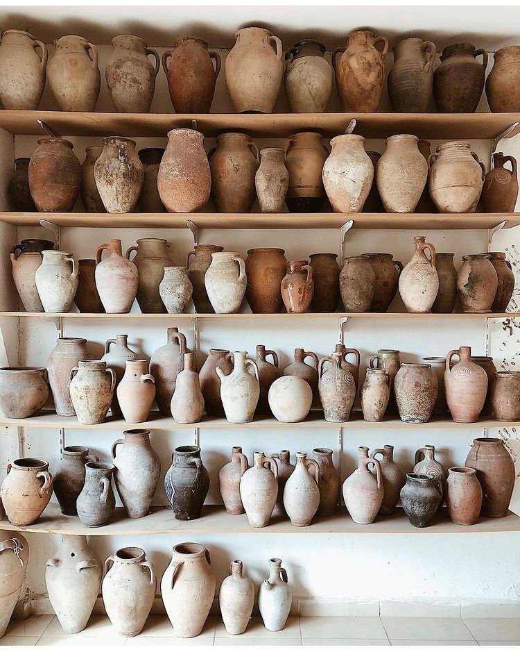 Collection of handcrafted terracotta vases in assorted shapes and natural clay finishes displayed on wooden shelves